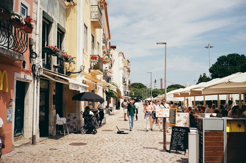 a group of people walking down a street next to tall buildings