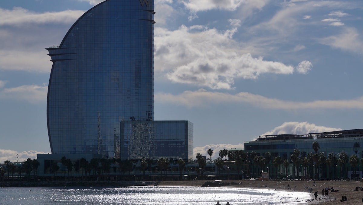 people are walking on the beach in front of a tall building