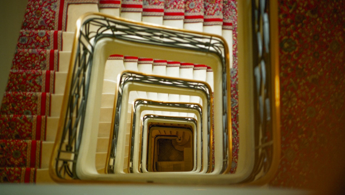 Looking down a spiral staircase with patterned carpet