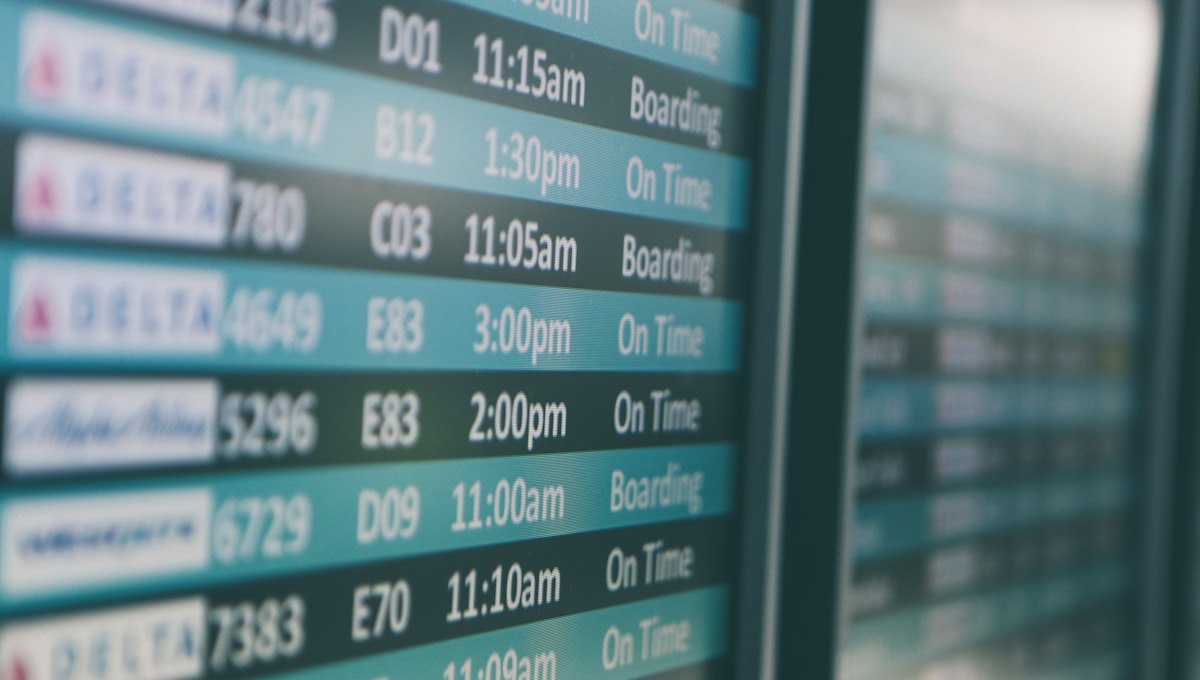 Airport departures timetable showing Delta and Alaska Airlines flights on time and boarding