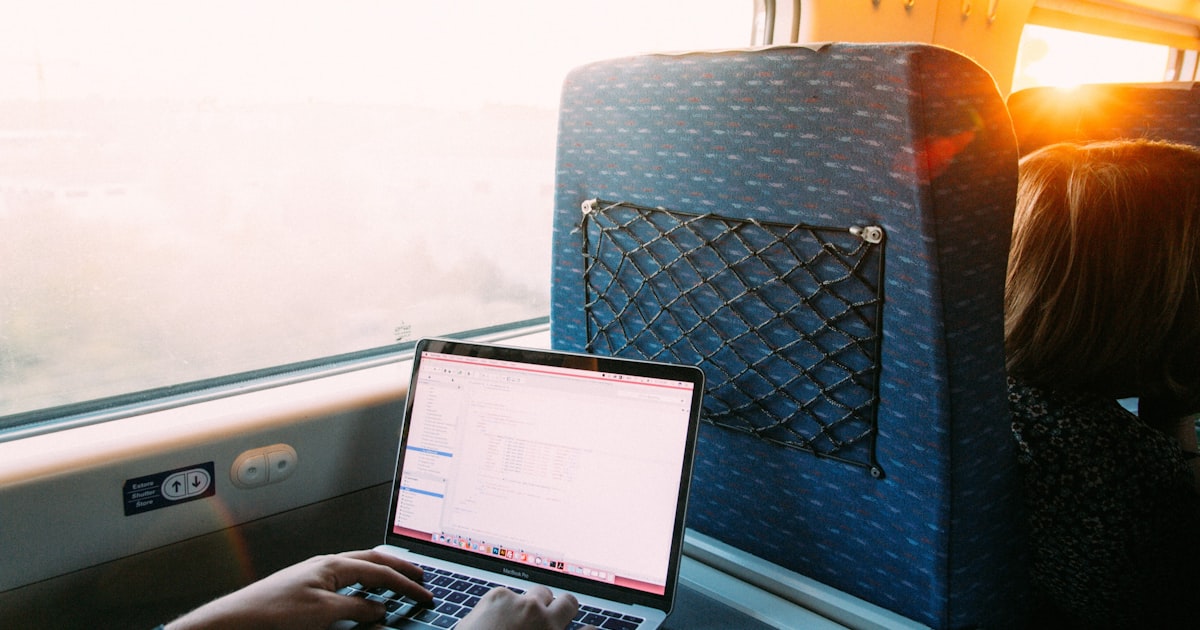 person using macbook pro on blue and white chair